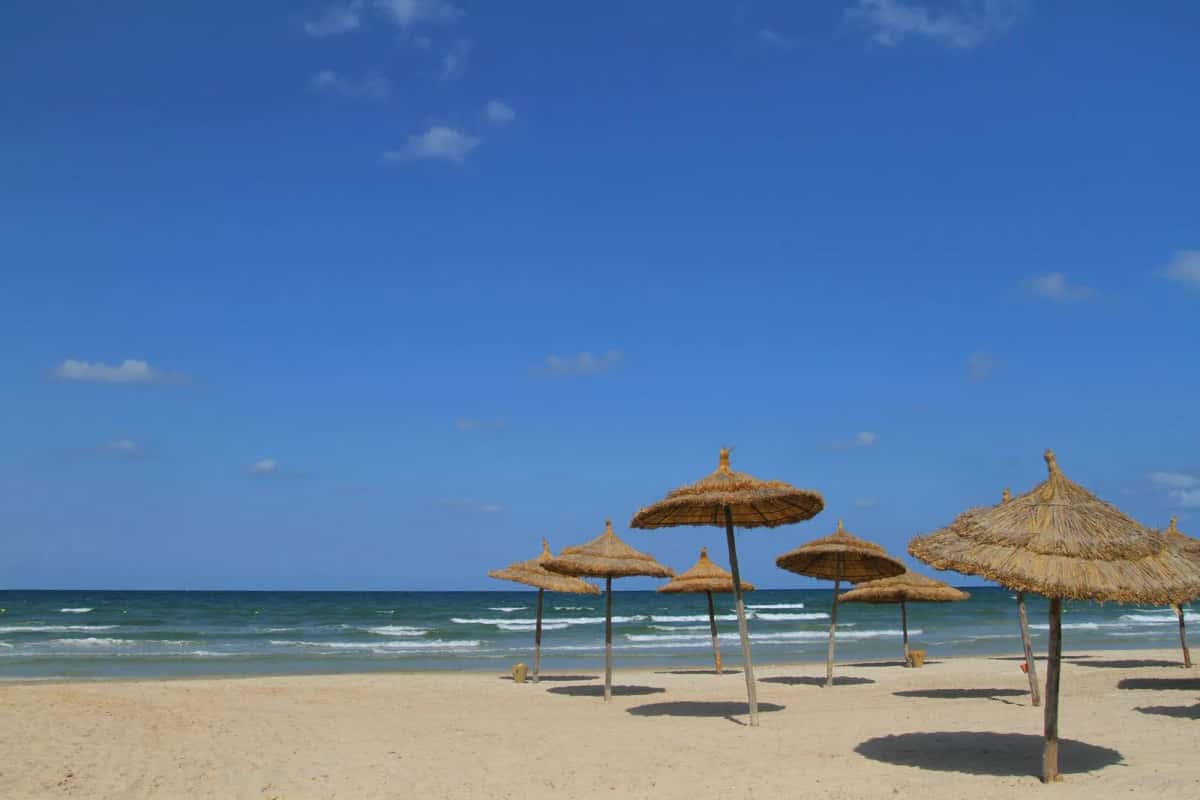 Plage de sable blanc avec parasols au soleil, Tunisie