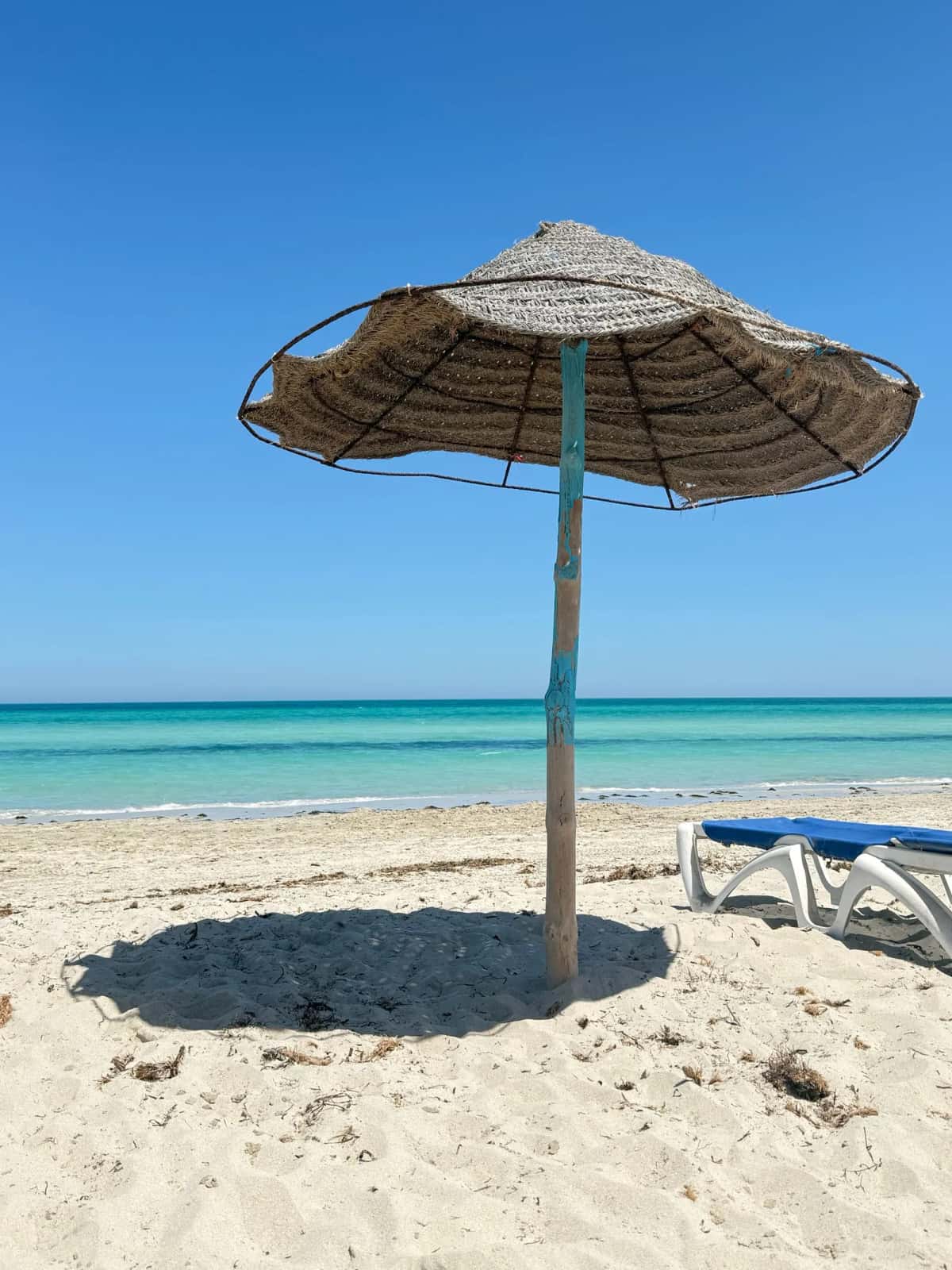 Plage ensoleillée avec parasol en paille et ciel bleu en Tunisie