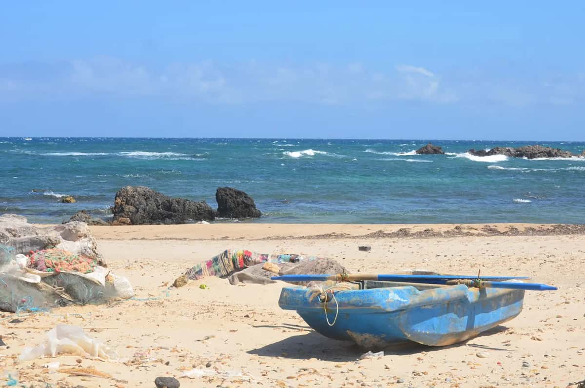 Barque de pêche bleue échouée sur le sable d'une plage tunisienne, en septembre