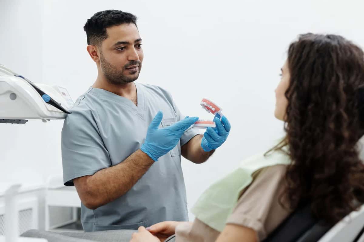Dentiste expliquant un traitement à une patiente à l'aide d'un modèle de dentition