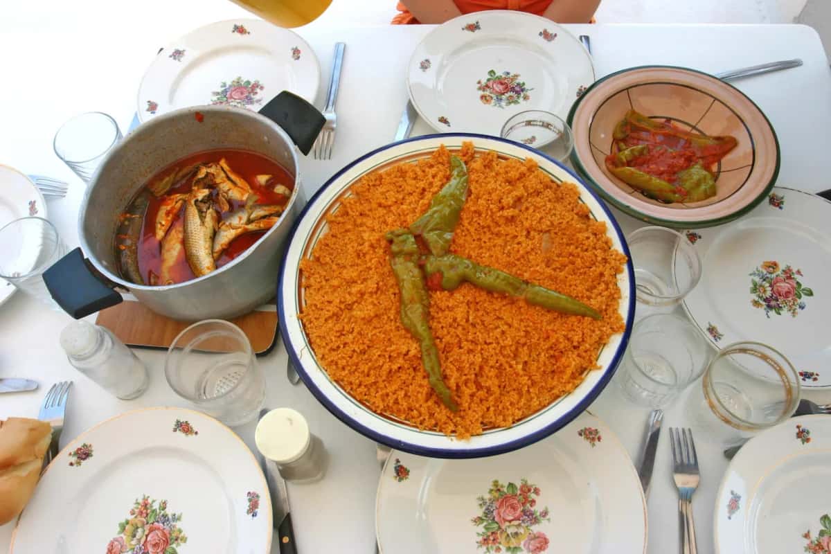 Couscous au poisson garni d'un piment vert, avec la sauce de poisson à côté