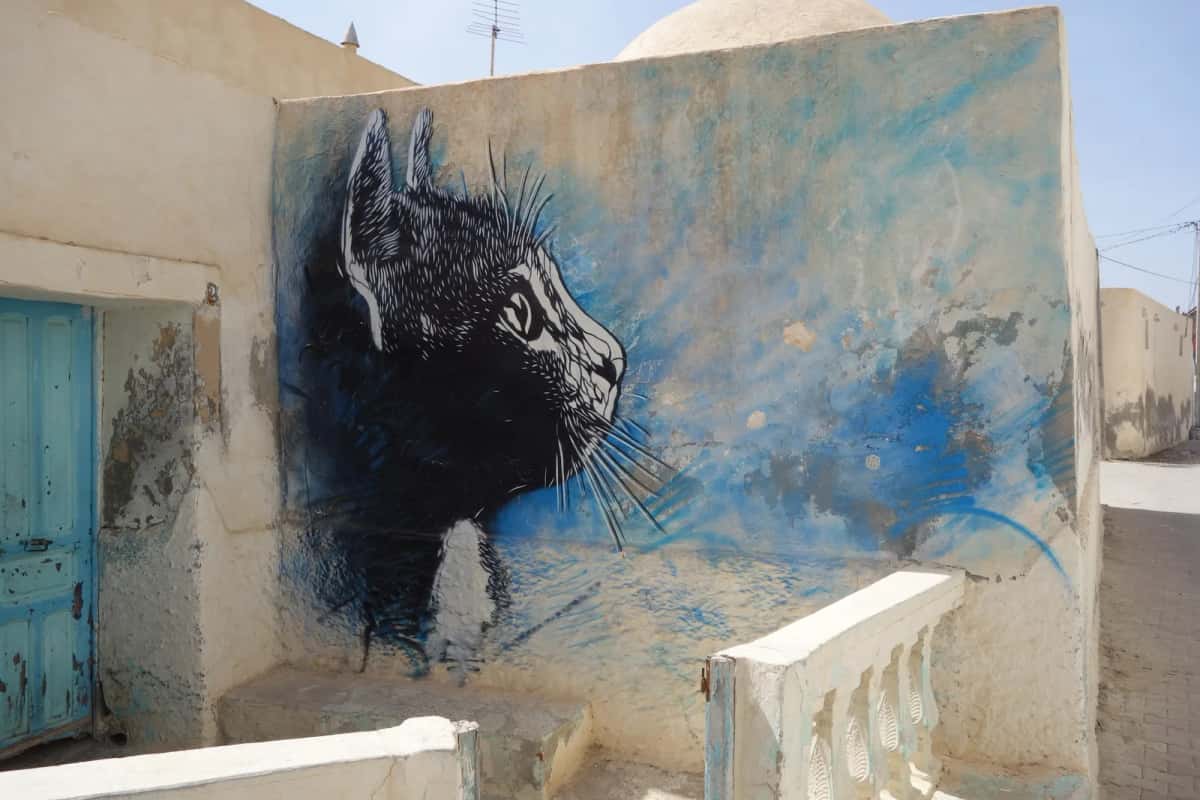 Pochoir de chat noir et bleu de C215 sur un mur à Erriadh, Djerbahood, Djerba