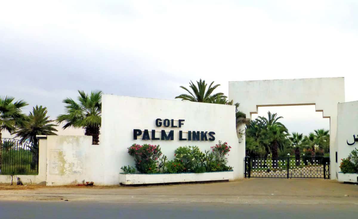 Entrée du golf Palm Links à Monastir : mur blanc portant l'enseigne et palmiers
