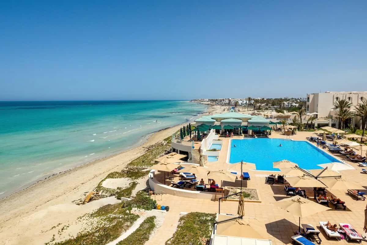 Vue aérienne de la plage de sable, de la piscine et des parasols de l'Ulysse Djerba Thalasso & Spa à Mezraia