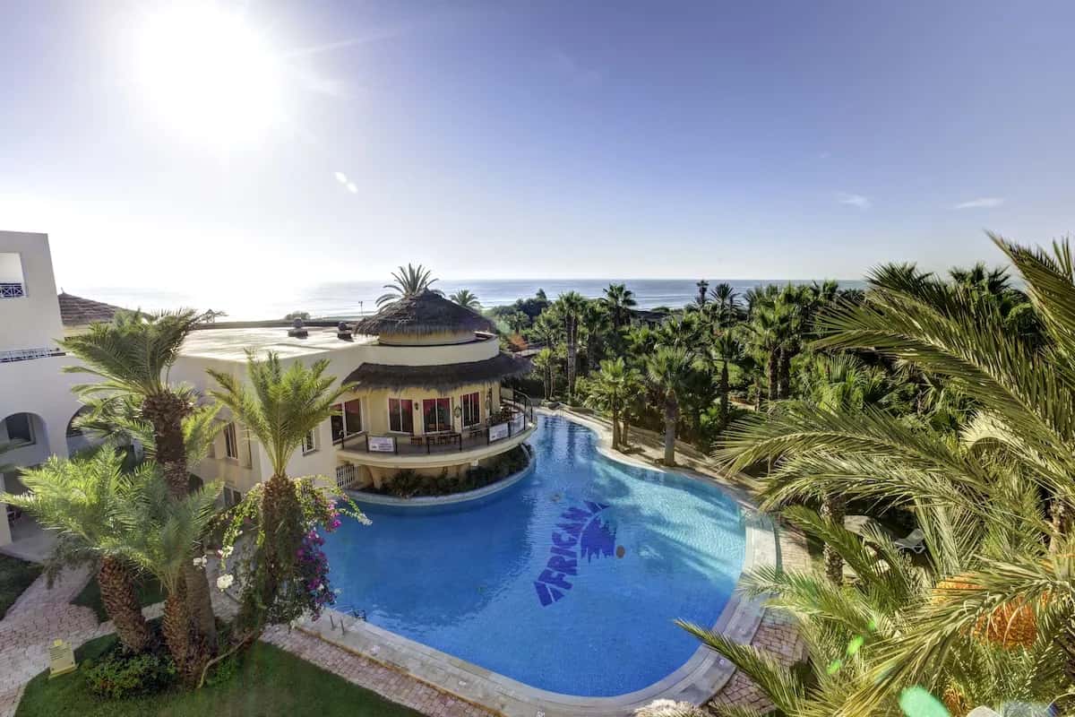Piscine en forme de lagon entourée de palmiers au Magic Life Africana, Yasmine Hammamet