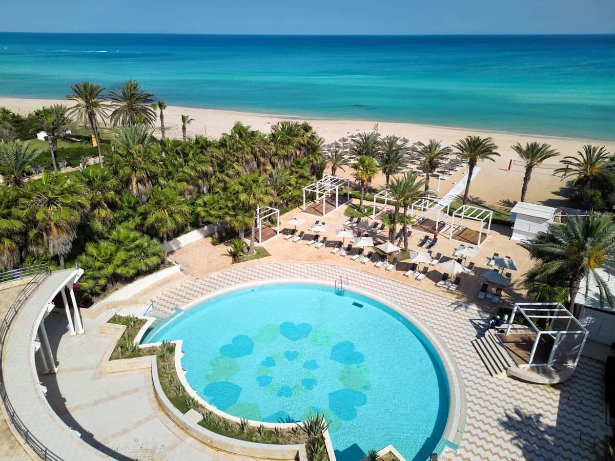 Vue aérienne de la piscine ronde, des palmiers et de la plage du Nahrawess Resort & Thalasso à Hammamet