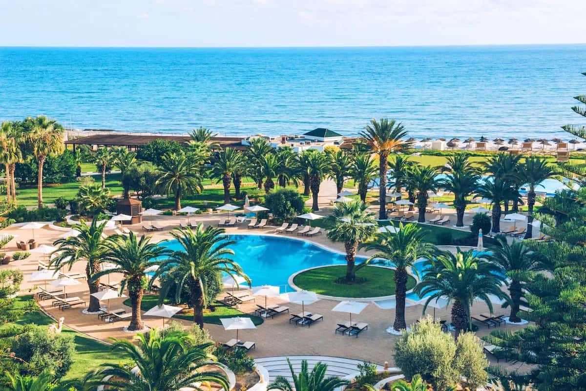 Piscine entourée de palmiers et mer au loin à l'Iberostar Selection Kantaoui Bay, Port El Kantaoui