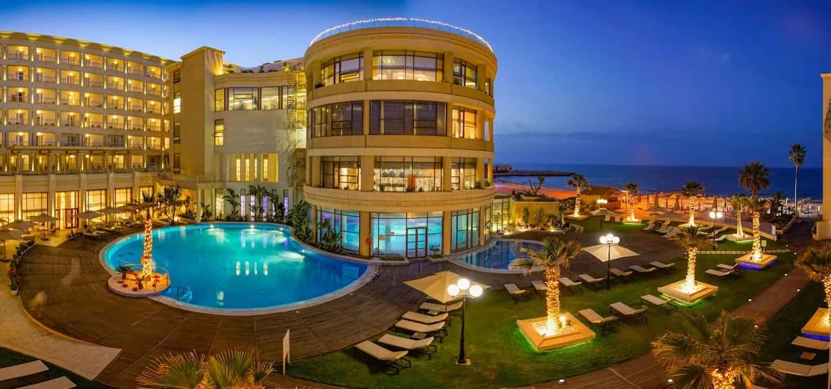Façade éclairée et piscine du Sousse Palace Hotel & Spa au crépuscule, Sousse