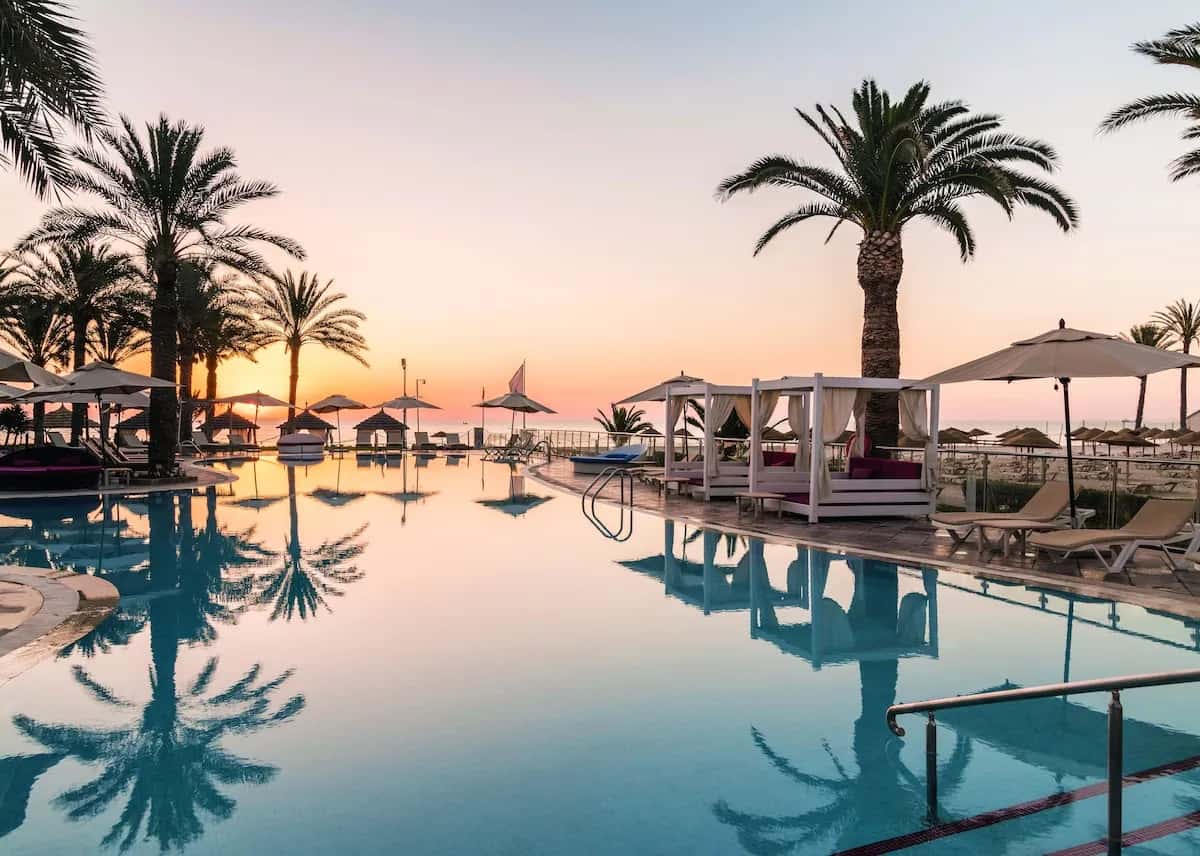 Piscine et palmiers au coucher du soleil au TUI Blue Scheherazade, hôtel réservé aux adultes à Sousse
