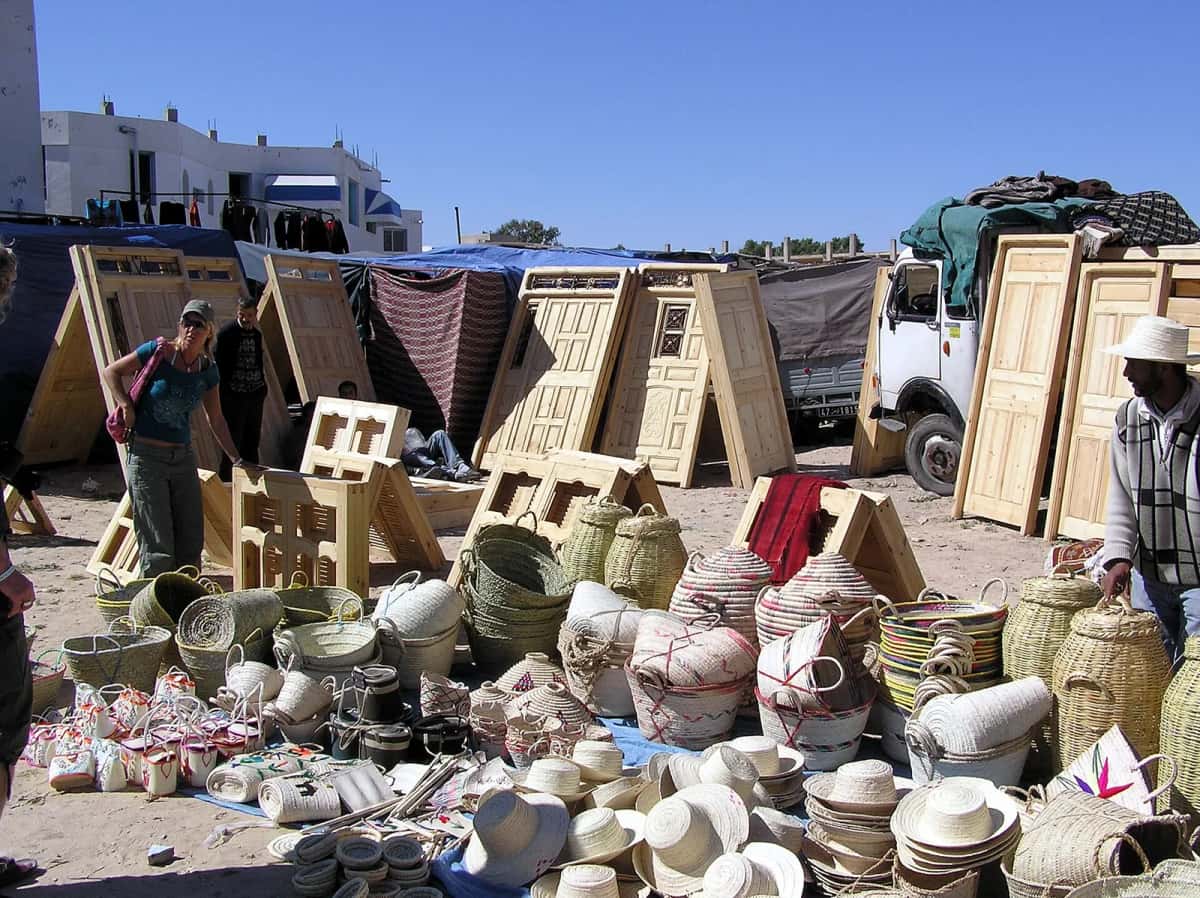 Étal de paniers, chapeaux de paille et portes en bois sculptées sur le marché de Houmt Souk, à Djerba