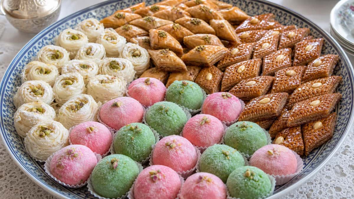Plateau de pâtisseries tunisiennes : baklawa en losanges, kaak warka blancs, mlabes roses et verts