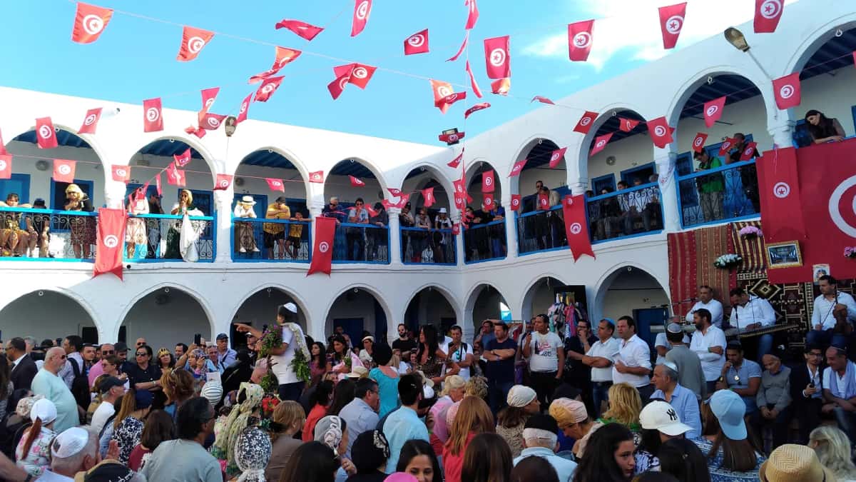 Pèlerins réunis dans la cour de la Ghriba sous les drapeaux tunisiens, pendant le pèlerinage, à Djerba