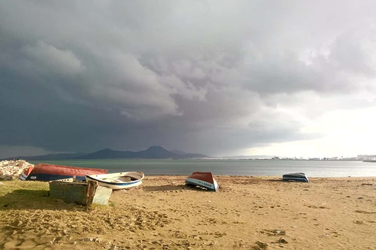 La plage de La Goulette sous un ciel d'orage, avec des barques échouées