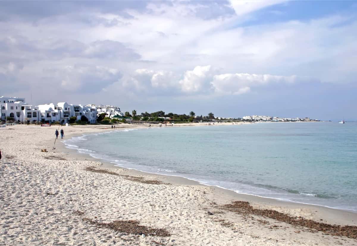 Plage de sable clair de Port El Kantaoui, mer calme et bâtiments blancs de la station en arrière-plan