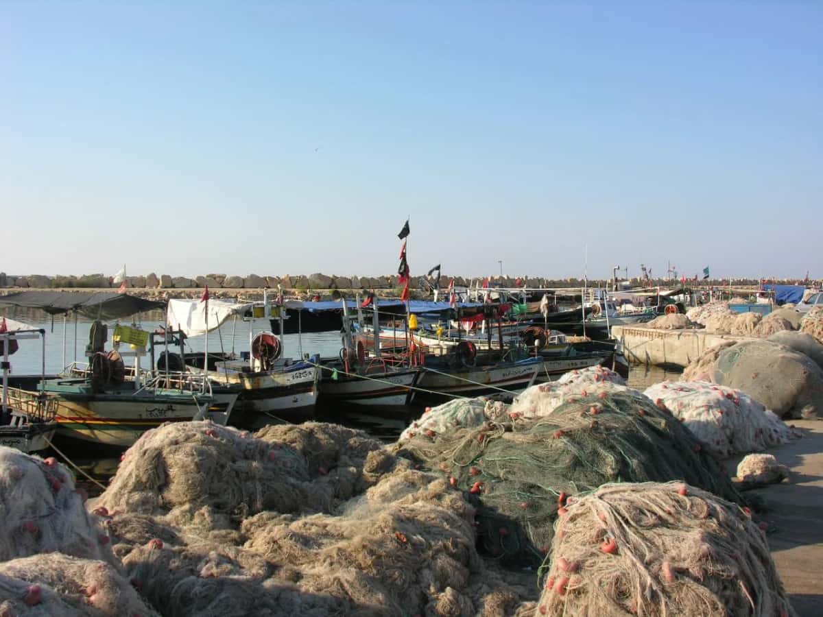 Barques de pêche amarrées derrière des tas de filets dans le port de Houmt Souk, à Djerba