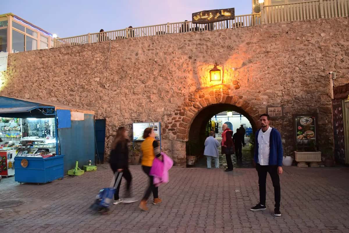 Passants sous la porte voûtée de la médina de Hammamet, en fin de journée