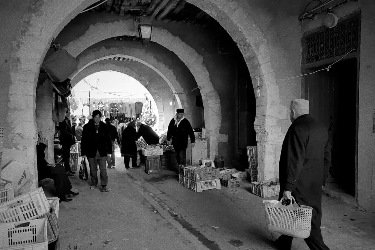 Passage voûté d'un souk de la médina de Sfax, avec marchands et passants