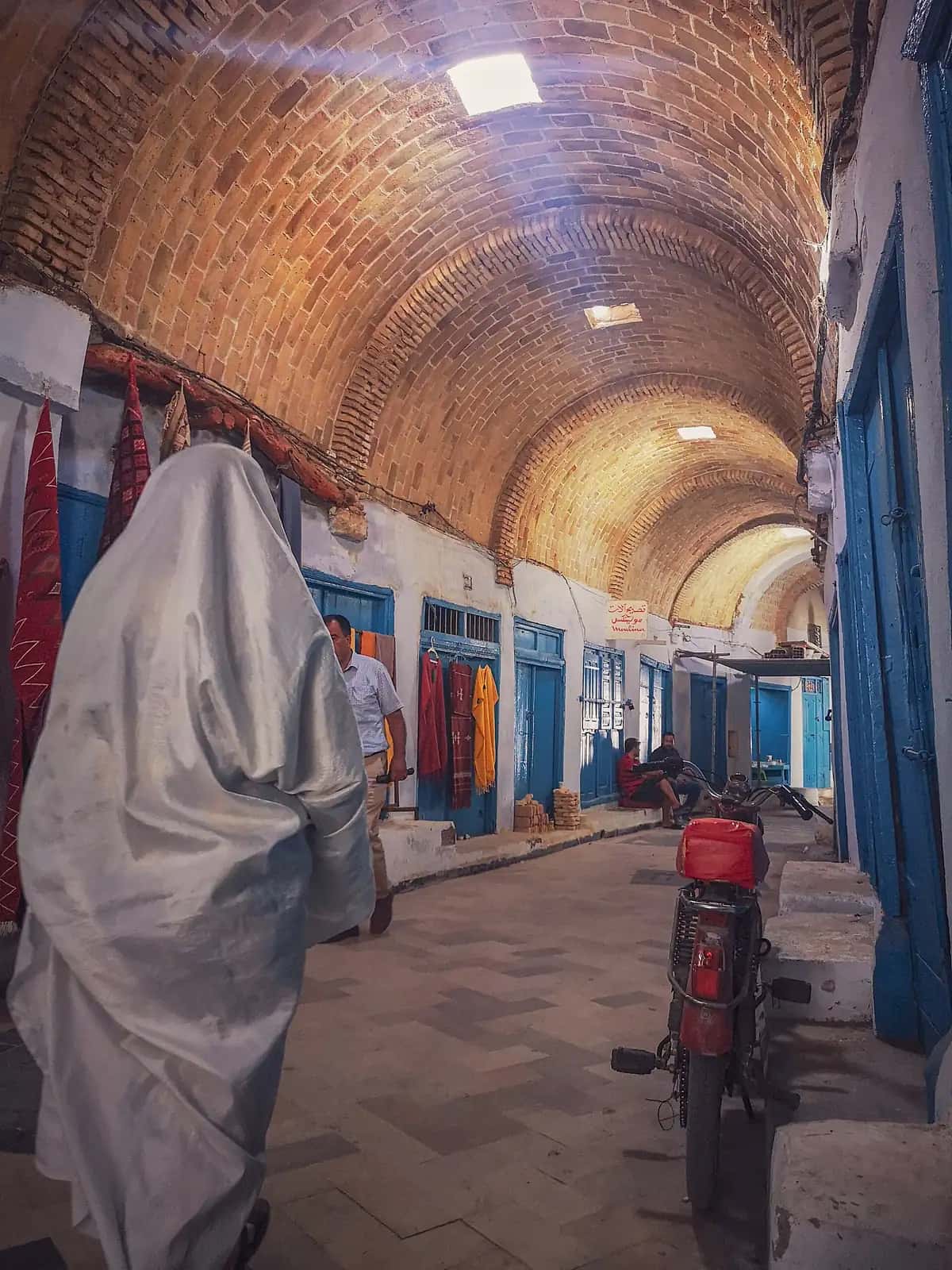 Souk voûté de la médina de Kairouan, avec une passante en sefsari blanc