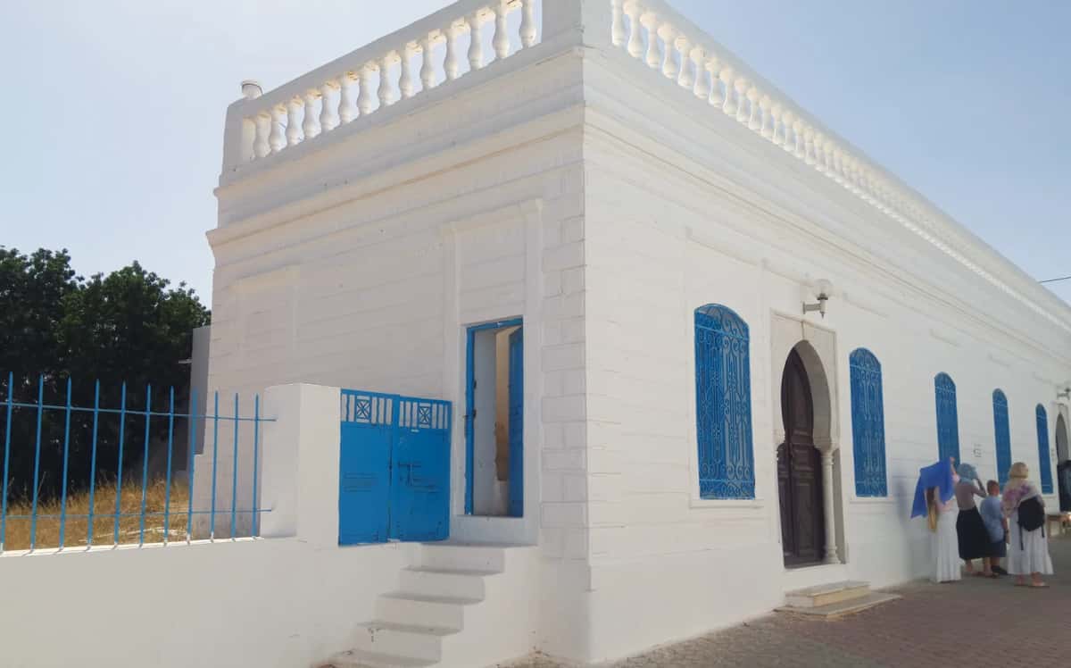 Façade blanche à fenêtres bleues et porte en arc de la synagogue de la Ghriba, à Erriadh, Djerba
